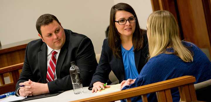 Two client counseling competitors speak with a potential client during a competition