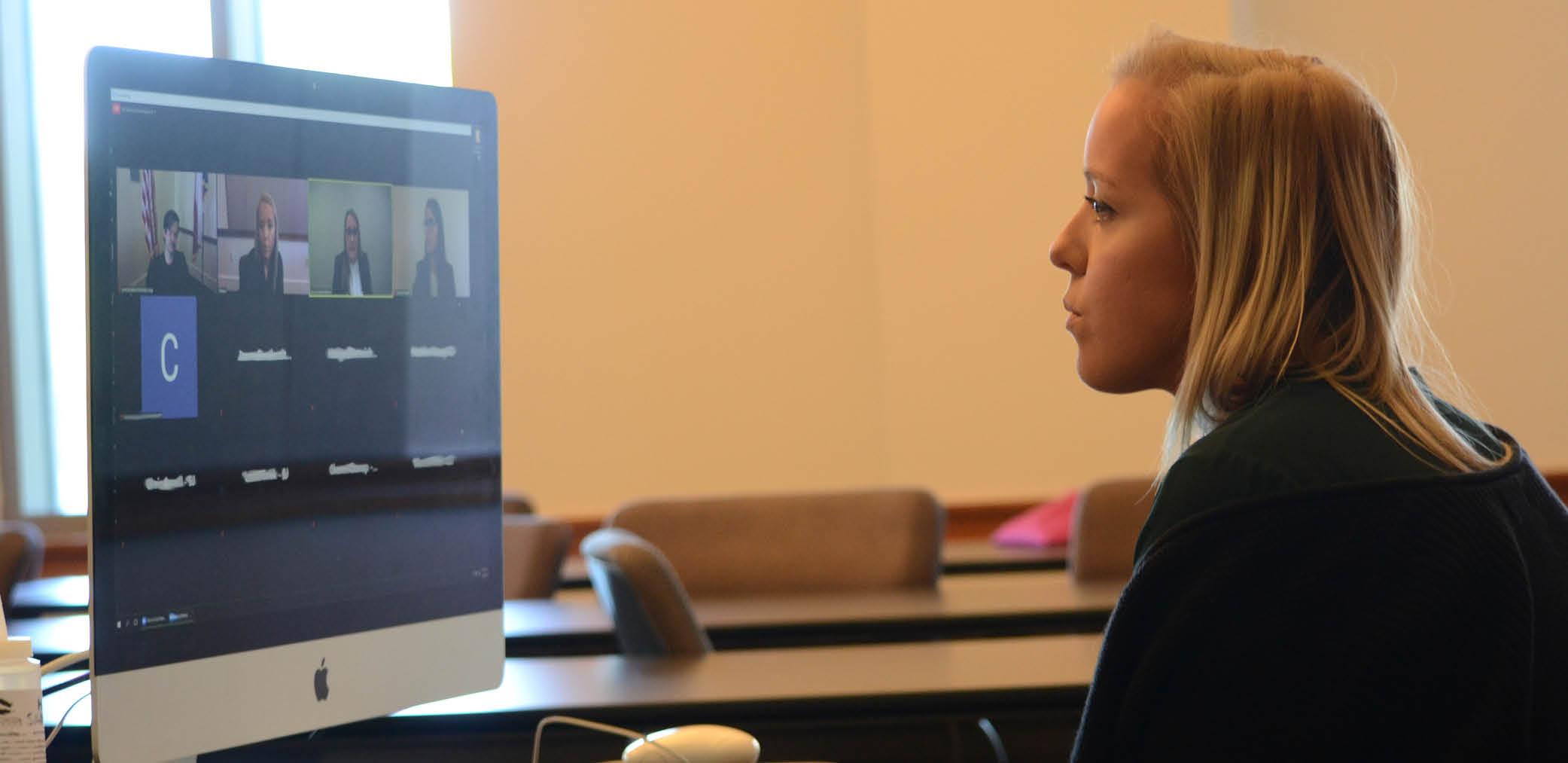Student looks at computer screen, watching conference call
