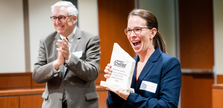 Winner of the paper chase excitedly holds trophy, while Baylor Law professors clap