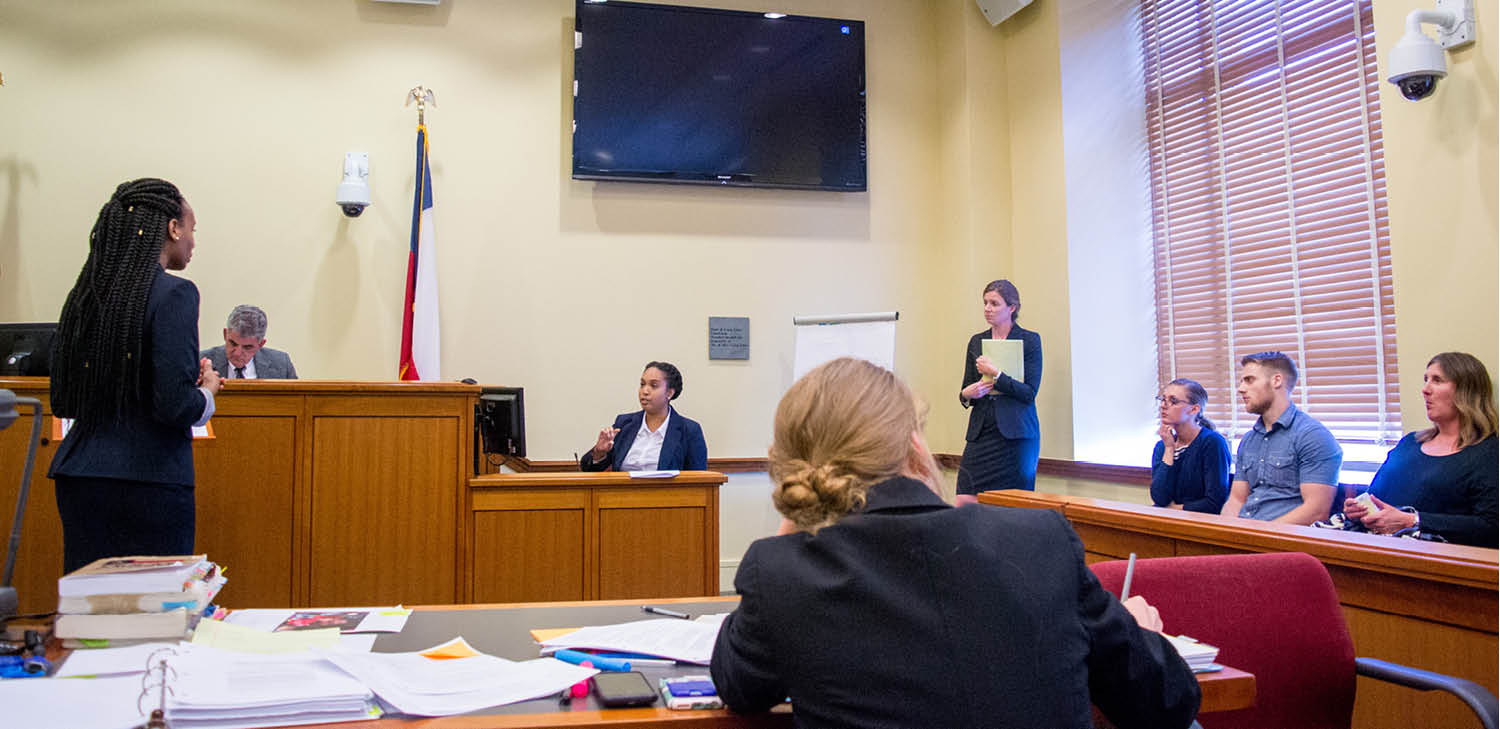 Student asks question of a witness, jury looks on, in Baylor Law courtroom