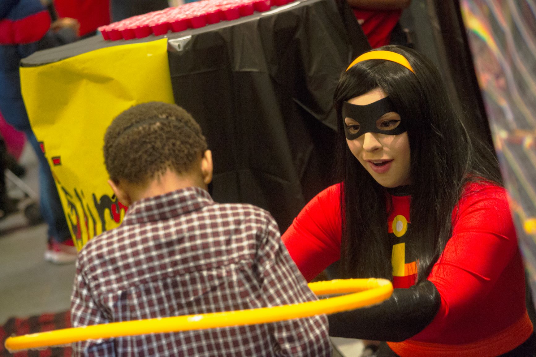 A Baylor Law student dressed as a character from Disney's "The Incredibles" helps small boy with hula-hoop.