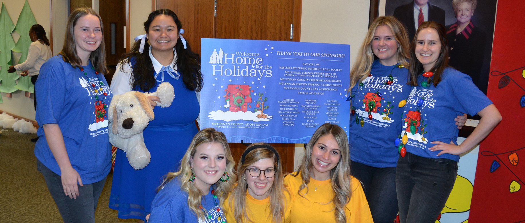 Baylor Law Students - Holding Snoopy-themed items or wearing Charlie Brown t-shirts, pose with a sign from Adoption Day 2022