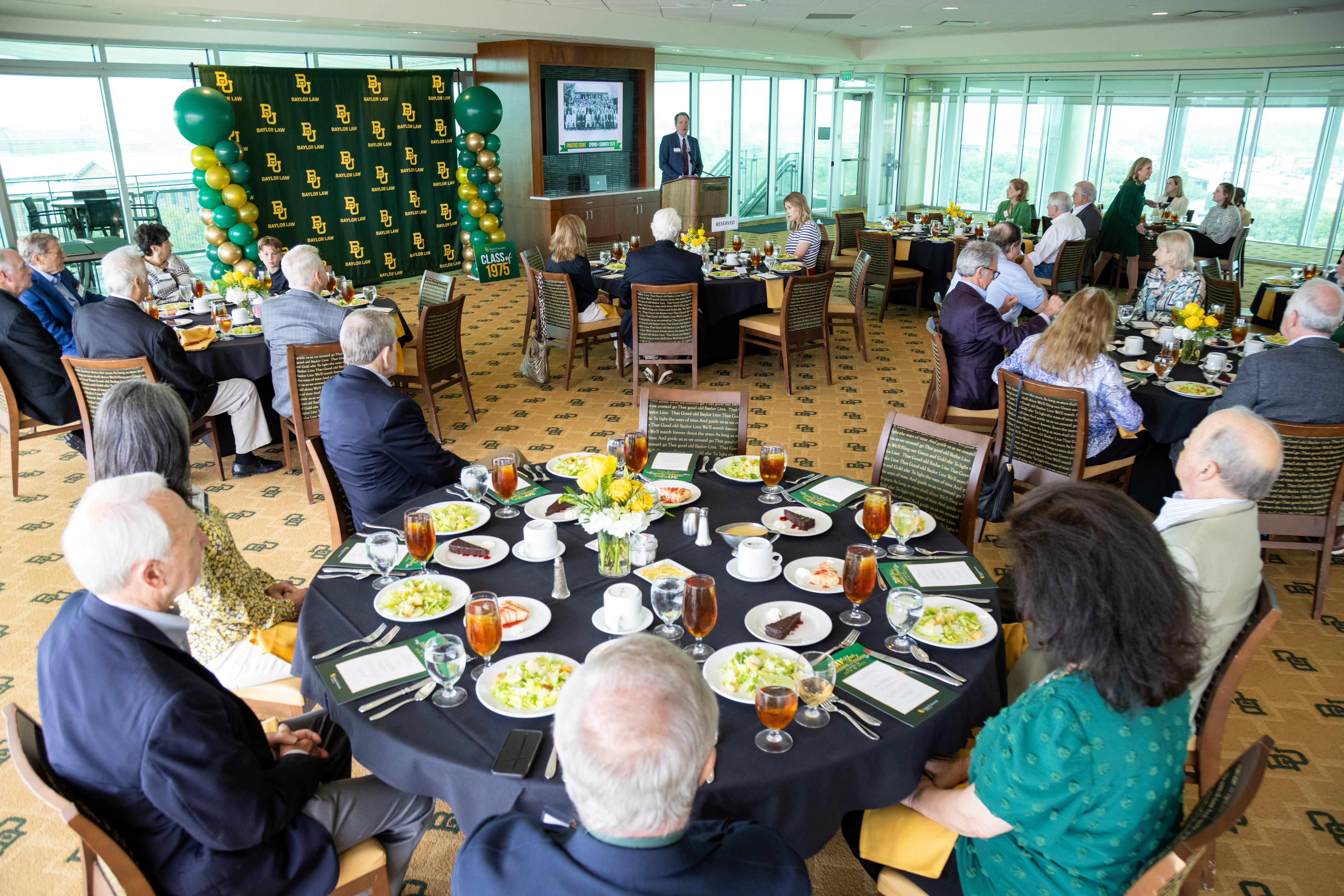 Photo of Dean Jeremy Counseller speaking before reunion attendees who are seated at tables eating at the 50th reunion