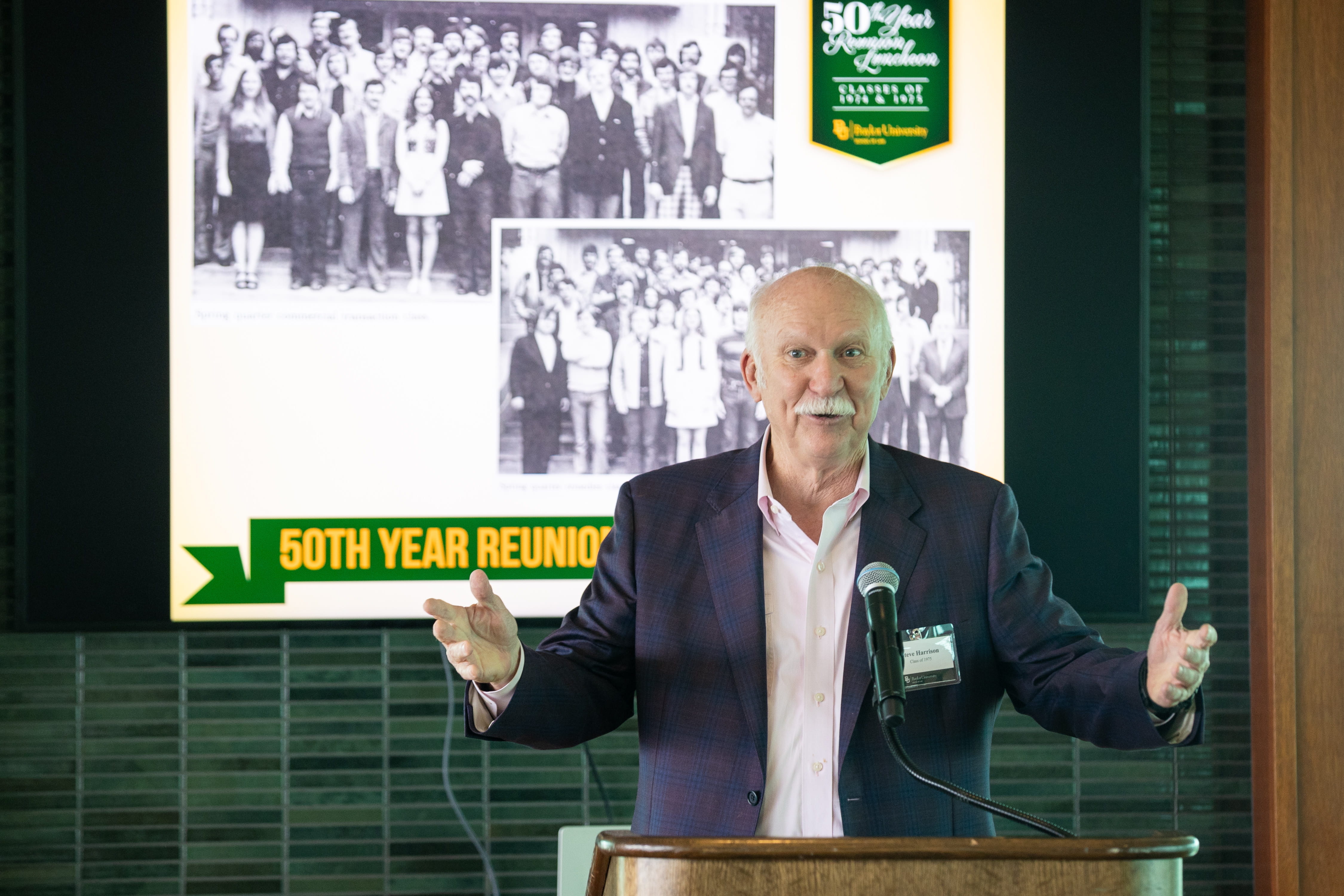 A speaker at the Baylor Law School 50th reunion in 2025, in front of screen showing pictures of the class of 1974
