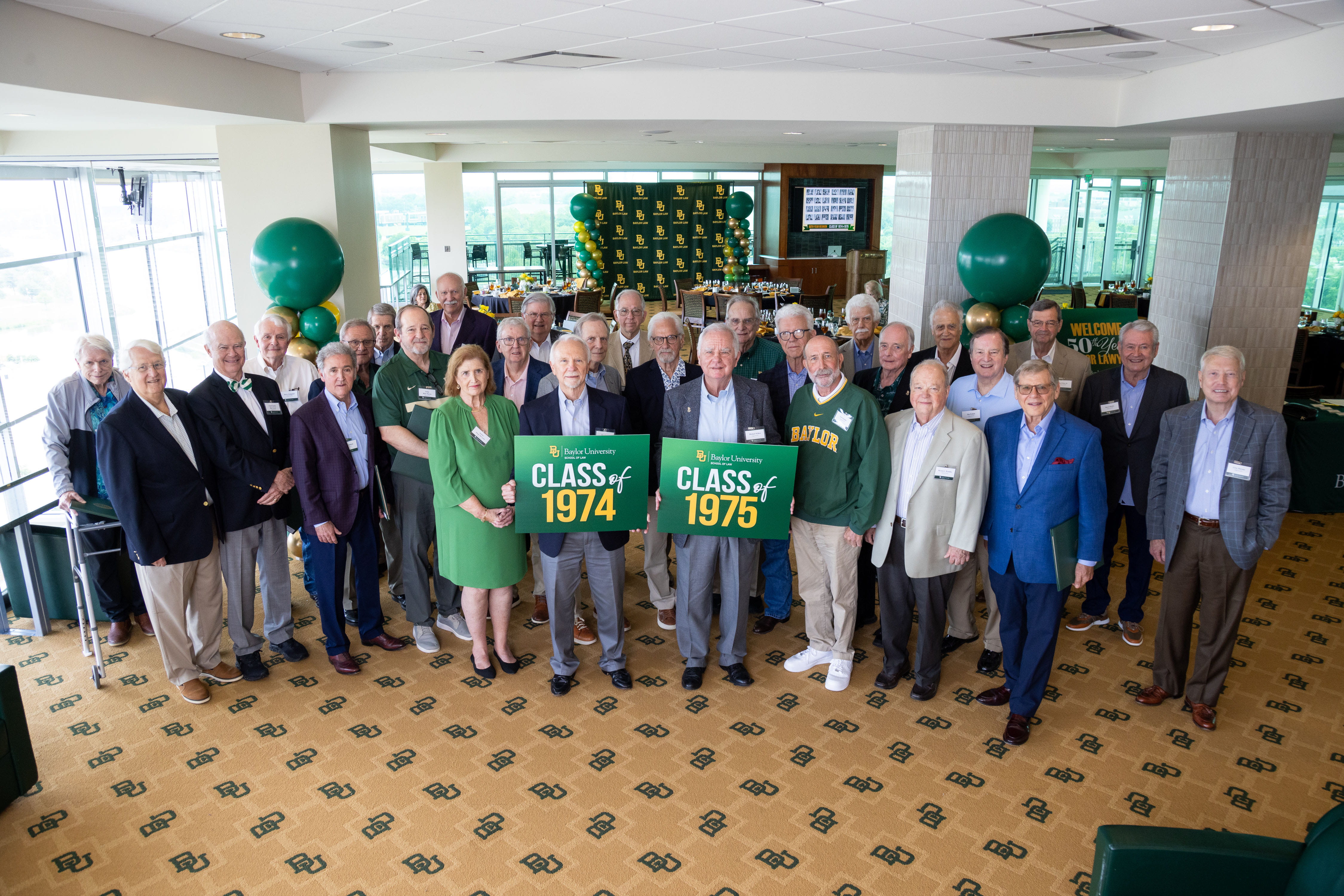 Members of the classes of 1974 and 1975 holding reunion signs, pose at the Baylor Club