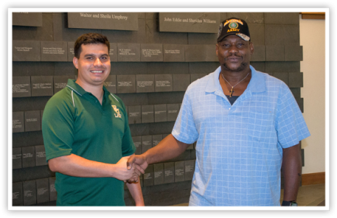 Student shaking hands with veteran on the first floor of the Law Center
