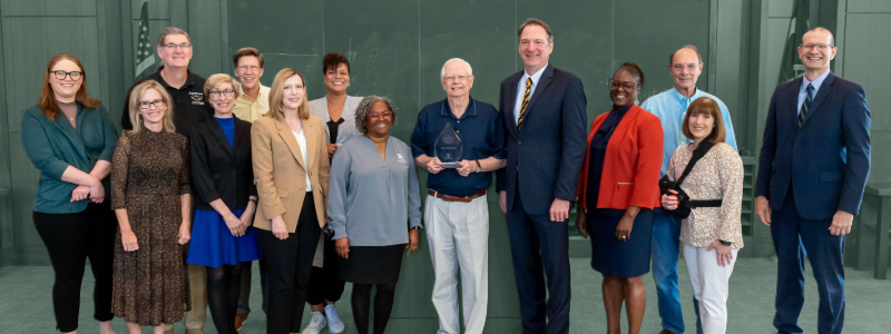 Professor of Law Tom Featherston poses in front of his classroom with multiple Baylor Law School Faculty members